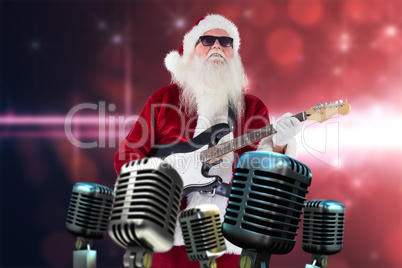 Composite image of santa claus plays guitar with sunglasses