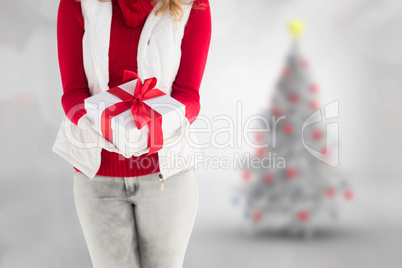 Composite image of festive blonde holding a gift