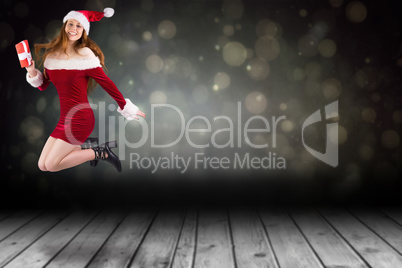 Composite image of festive redhead jumping with gift