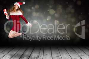 Composite image of festive redhead jumping with gift