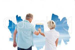 Composite image of happy older couple painting a sky