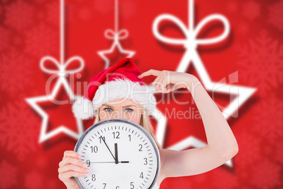 Composite image of festive blonde holding a clock
