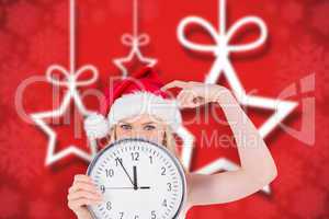 Composite image of festive blonde holding a clock