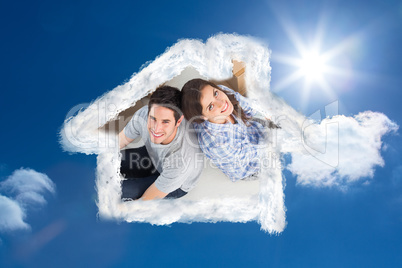 Composite image of overview of a happy couple sitting back-to-ba