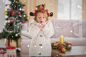 Composite image of festive little girl blowing over hands