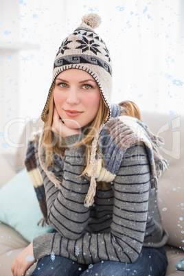 Composite image of cute blonde in winter hat sitting on couch posing