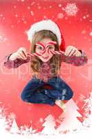 Composite image of happy little girl in santa hat holding candy canes