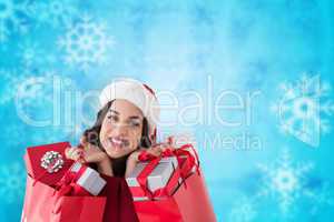 Composite image of excited brunette holding shopping bags full o
