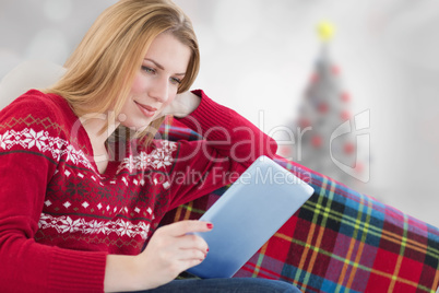 Composite image of woman using her tablet on the couch