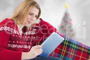 Composite image of woman using her tablet on the couch