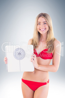 Fit blonde in red bikini showing scales