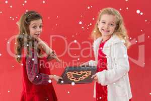 Composite image of festive little girls holding cookies