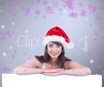 Composite image of festive brunette leaning on large poster