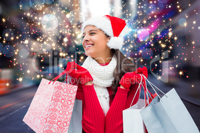 Composite image of festive brunette holding shopping bags