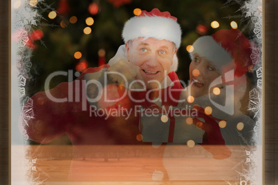 Composite image of festive mature couple holding gift