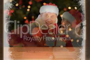 Composite image of festive mature couple holding gift