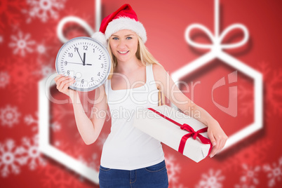 Composite image of festive blonde holding a clock and gift