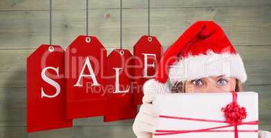 Composite image of festive blonde holding a gift