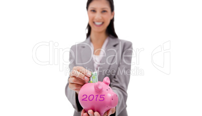 Composite image of money being put into piggy bank by smiling bu