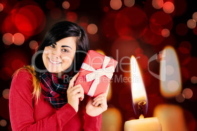 Composite image of excited brunette holding red gift