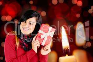 Composite image of excited brunette holding red gift