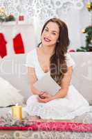 Composite image of smiling brunette on the couch reading letter at christmas