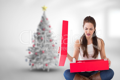 Composite image of unhappy brunette opening present