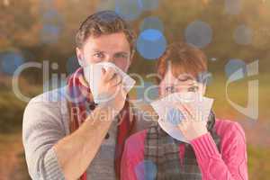 Composite image of couple blowing noses into tissues