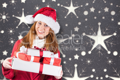 Composite image of festive redhead holding pile of gifts