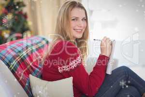 Composite image of smiling blonde writing while sitting on the s