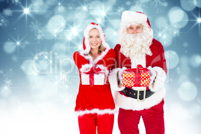 Composite image of santa and mrs claus smiling at camera offerin