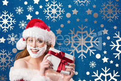 Composite image of festive redhead in foam beard holding gift