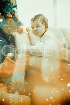 Composite image of cute baby boy on couch at christmas Composite image of cute baby boy on couch at christmas