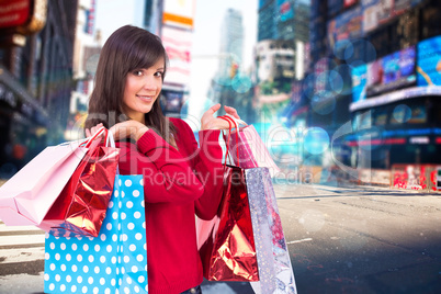 Composite image of smiling brunette holding shopping bags