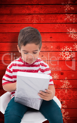 Composite image of cute little boy opening gift