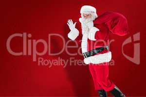 Composite image of santa holding a sack and waving