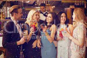 Composite image of attractive friends drinking cocktails togethe