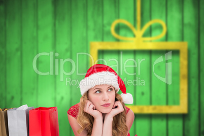 Composite image of thoughtful woman lying between shopping bags