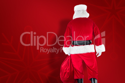 Composite image of rear view of santa claus holding a sack