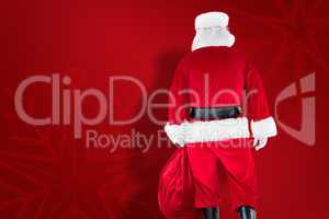 Composite image of rear view of santa claus holding a sack