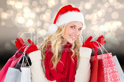 Composite image of happy festive blonde with shopping bags