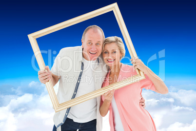 Composite image of older couple smiling at camera through pictur