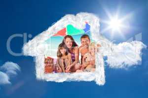 Composite image of family posing under a beach umbrella on the b