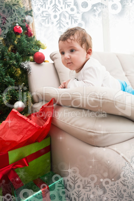 Composite image of cute baby boy on couch at christmas