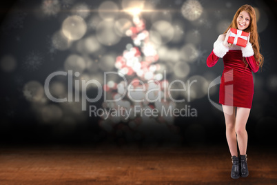 Composite image of festive redhead holding a gift