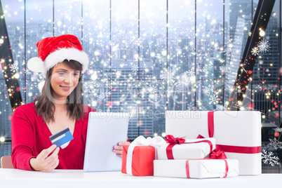Composite image of festive brunette shopping online with tablet