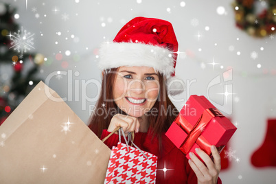 Composite image of festive redhead holding christmas gifts