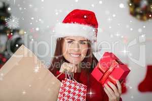 Composite image of festive redhead holding christmas gifts