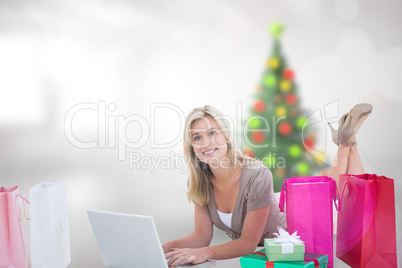 Composite image of happy blonde shopping online with laptop