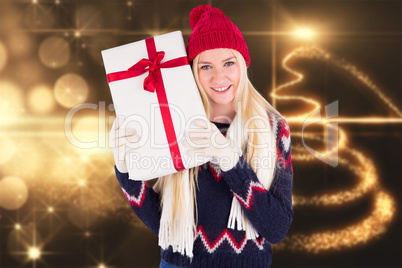 Composite image of festive blonde holding a gift